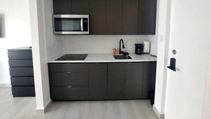 Eine moderne Küche mit dunklen Schränken, einer Edelstahl-Mikrowelle, einem Spülbecken und einer Kaffeemaschine.