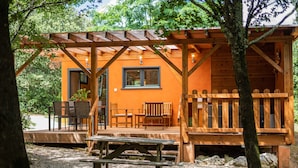 Uma cabana de madeira com varanda, área de estar externa e mesa para piquenique.