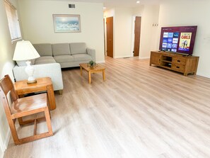 A living room with a sofa, a coffee table, a TV, and a wooden cabinet.