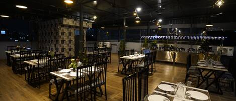 A restaurant with multiple dining tables set for guests, featuring a mix of wooden and metal chairs.