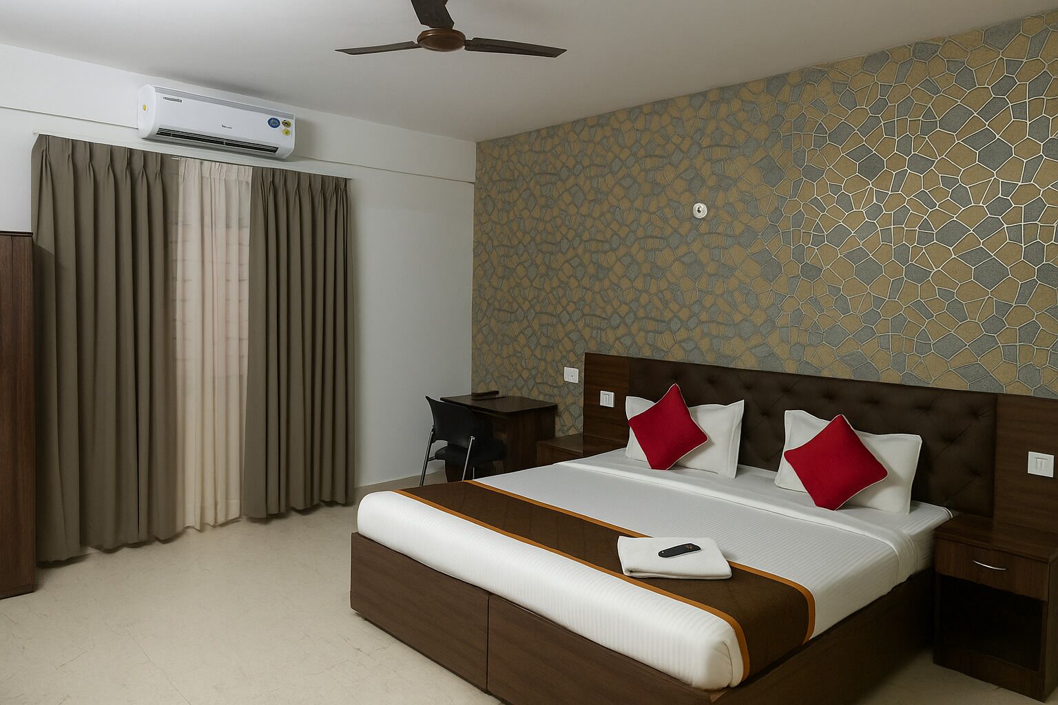 A hotel room with a bed, a desk, an air conditioner, and a ceiling fan.