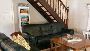 Un salon avec un canapé en cuir noir, une table basse en bois et un escalier.