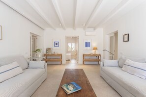 A spacious living room with two sofas facing each other, a coffee table in the center, and a hallway leading to another room.