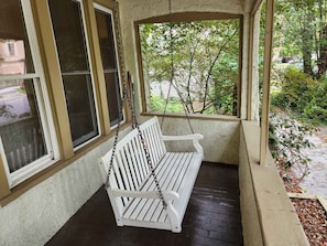 A porch with a white swing bench, a window, and a view of greenery. - Cozy 3 Bedroom House in Downtown Ithaca (Ithaca)