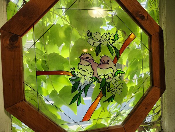 Un vitrail à motifs géométriques représentant deux oiseaux perchés sur une branche.