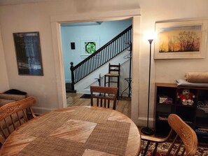 A dining area with a round table, chairs, a staircase, a bookshelf, and a framed picture on the wall. - Cozy 3 Bedroom House in Downtown Ithaca (Ithaca)