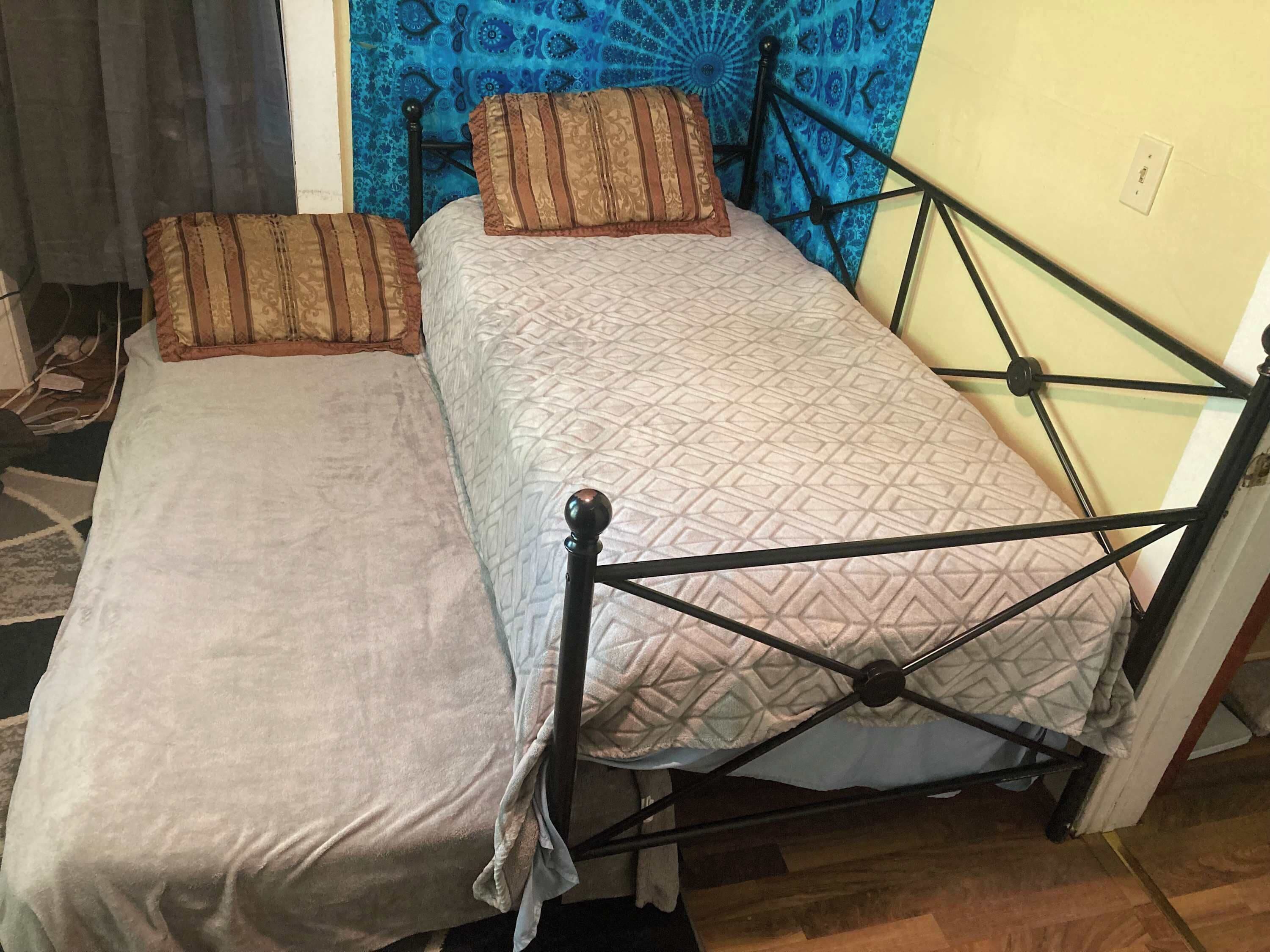 A room with two beds, one with a patterned bedspread and the other with a plain one.