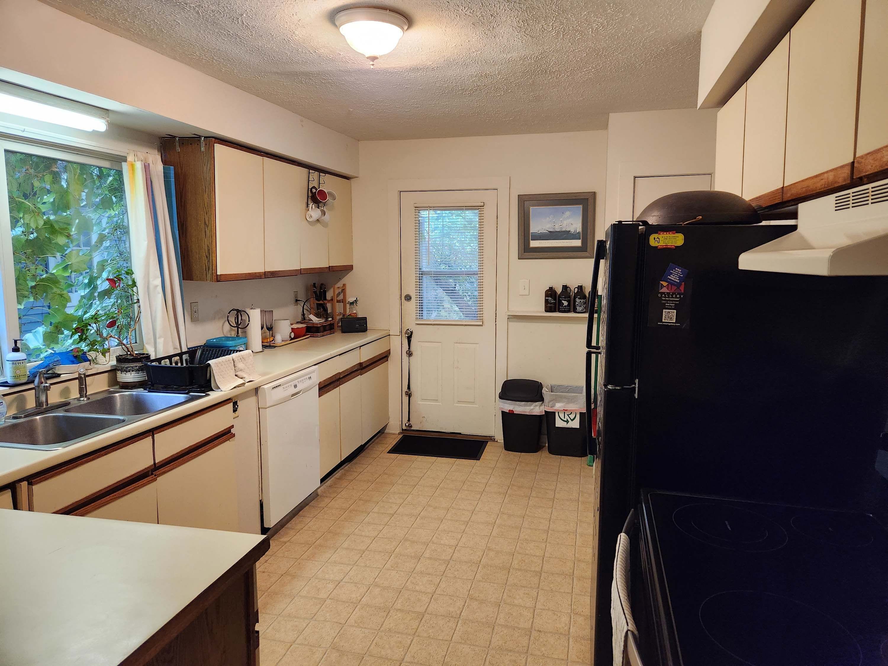 A kitchen with a dishwasher, sink, and a refrigerator.