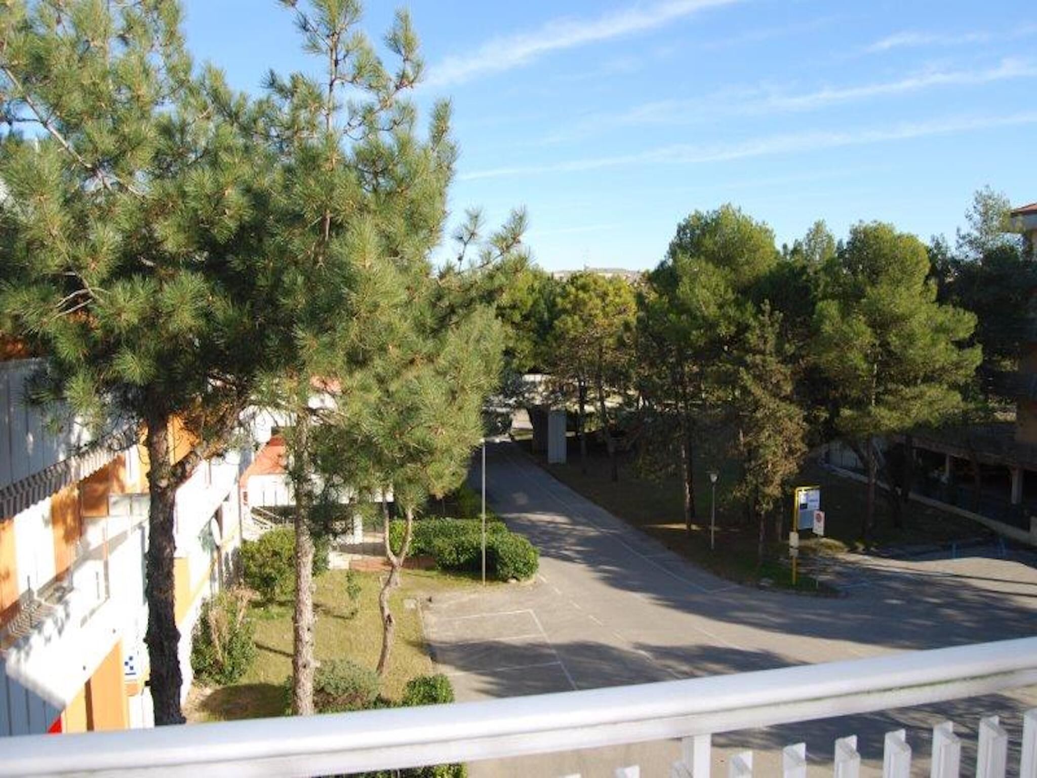 Une rue résidentielle bordée de maisons et d’arbres, avec un ciel dégagé.