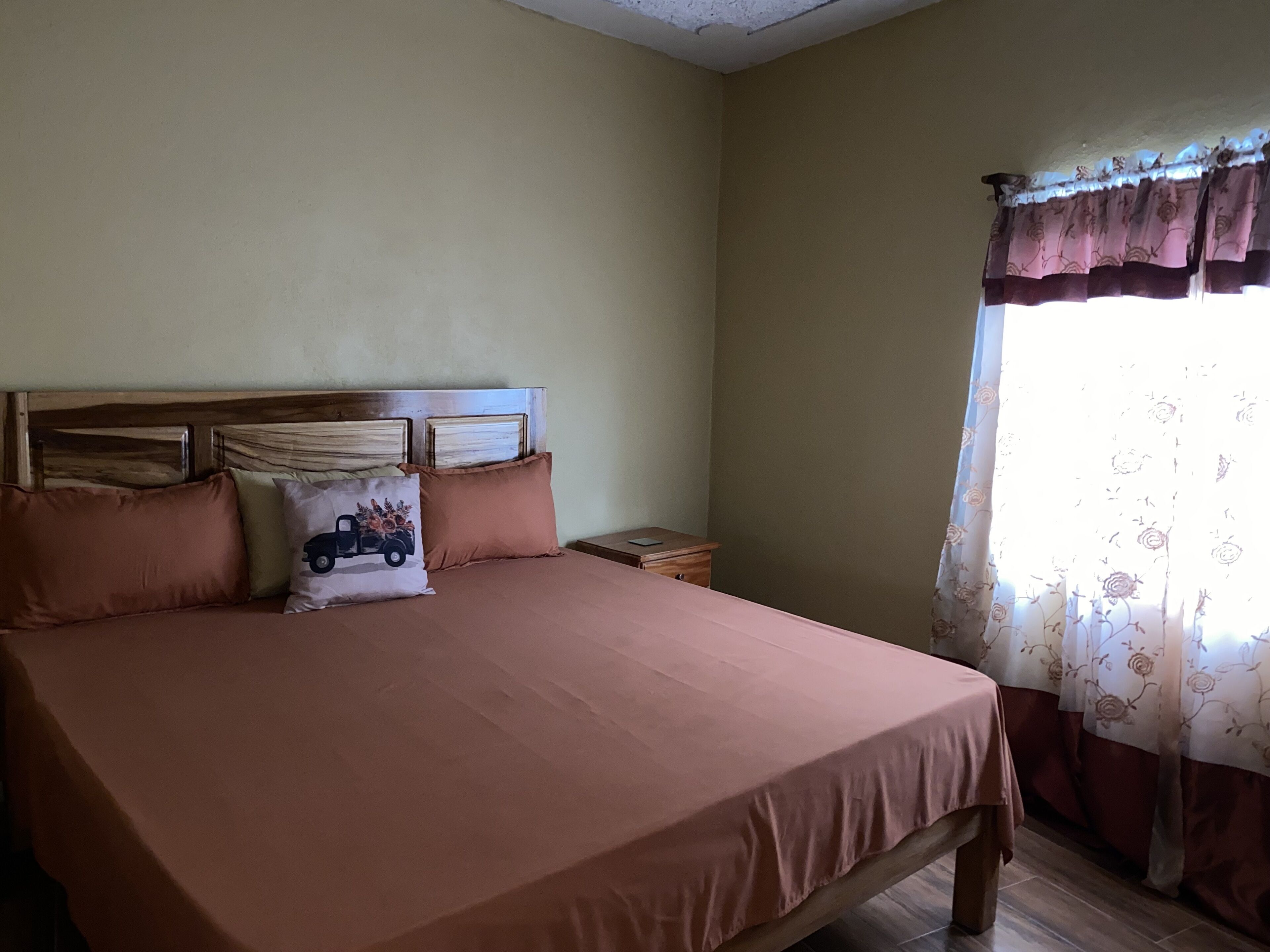 A bedroom with a large bed, a wooden headboard, and a nightstand.
