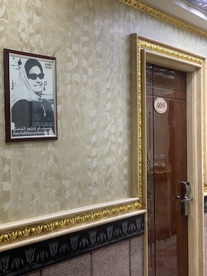 Une photographie encadrée accrochée au mur, une porte portant le numéro 409 et un motif décoratif en bordure.