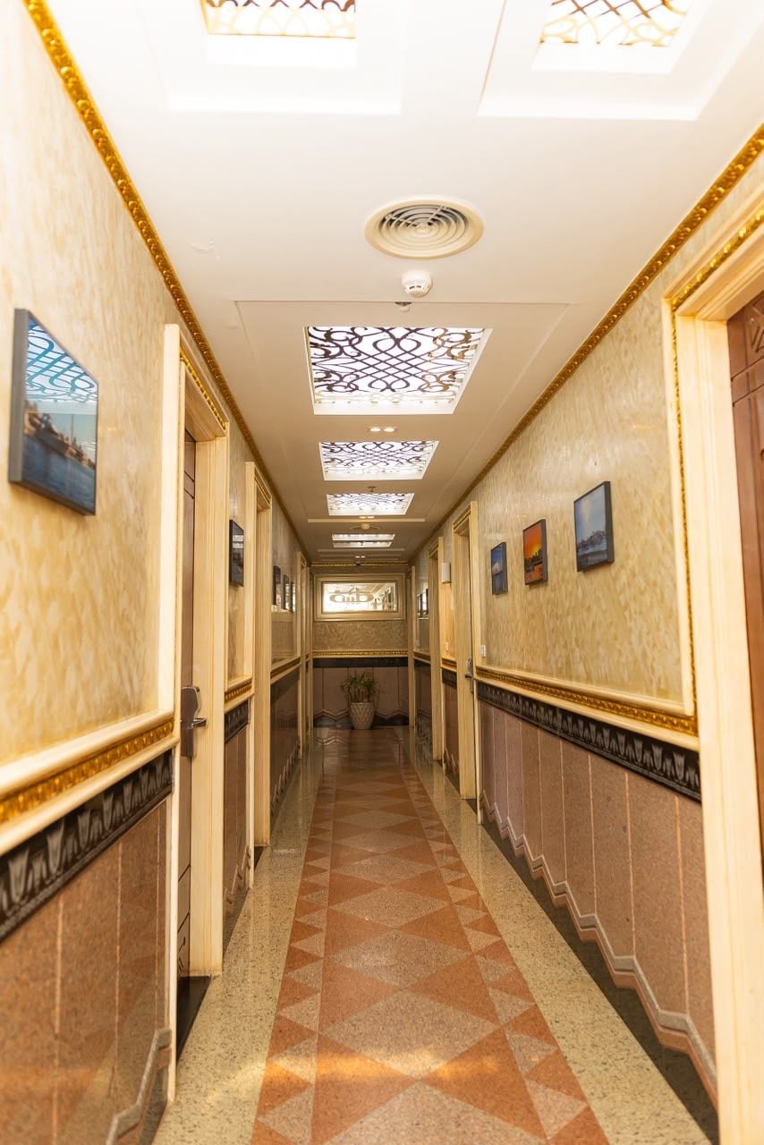Un pasillo de hotel con paredes estampadas, piso a cuadros y cuadros enmarcados.