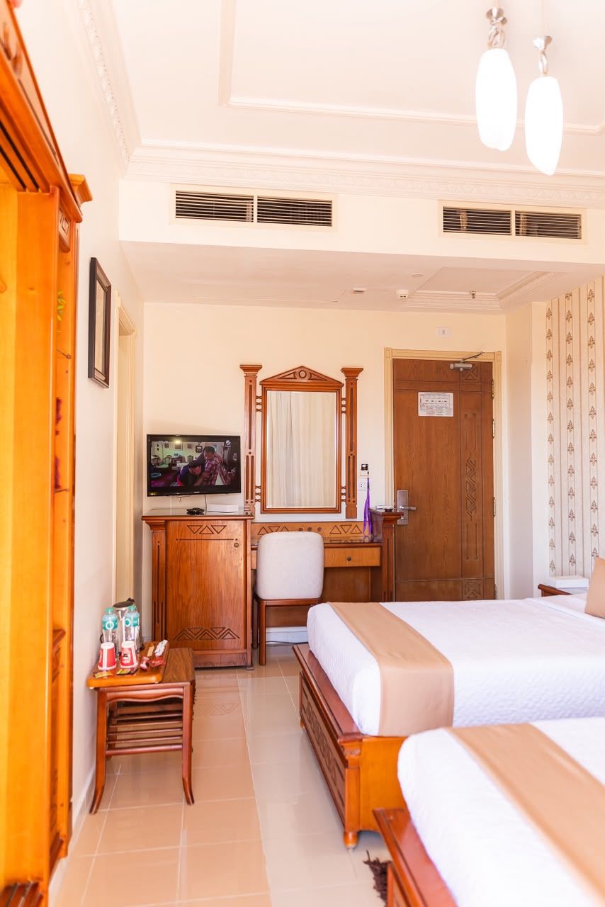 A hotel room with a bed, a desk, a television, and a wardrobe.