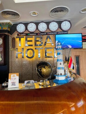 A hotel reception desk with clocks displaying times in Cairo, Makkah, London, Moscow, and New York.
