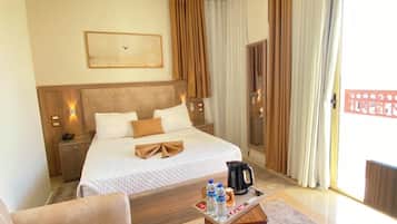 A hotel room with a bed, a desk, a chair, a coffee maker, and a large window with curtains.