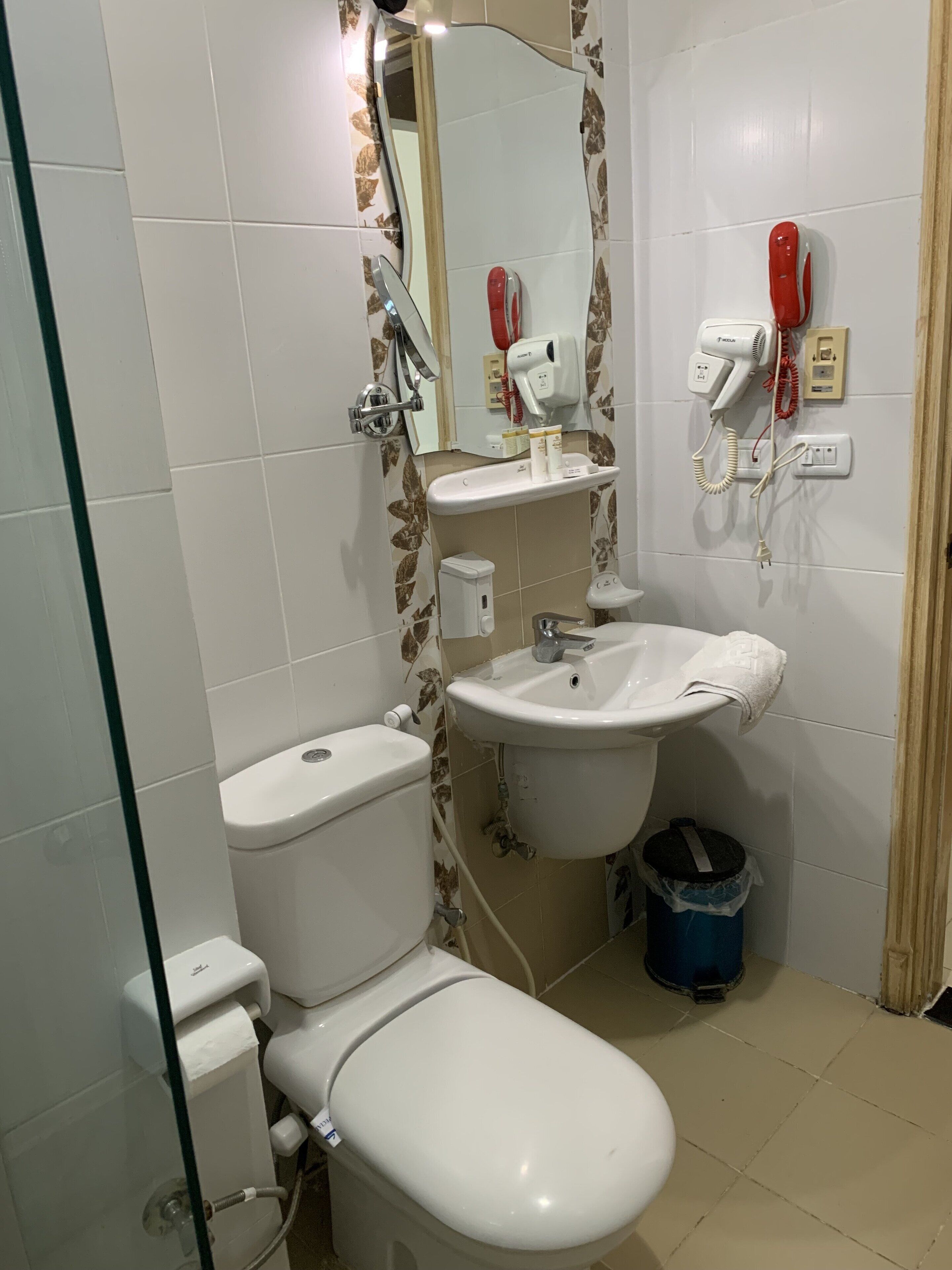 Ein Badezimmer mit Toilette, Waschbecken und zwei an der Wand befestigten Haartrocknern.