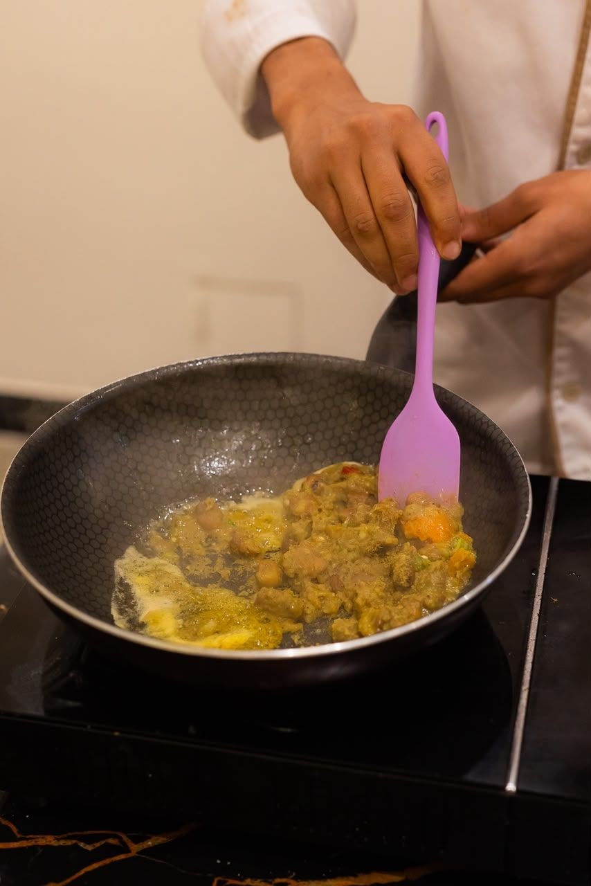 A person stirring a dish in a pan on a stove.