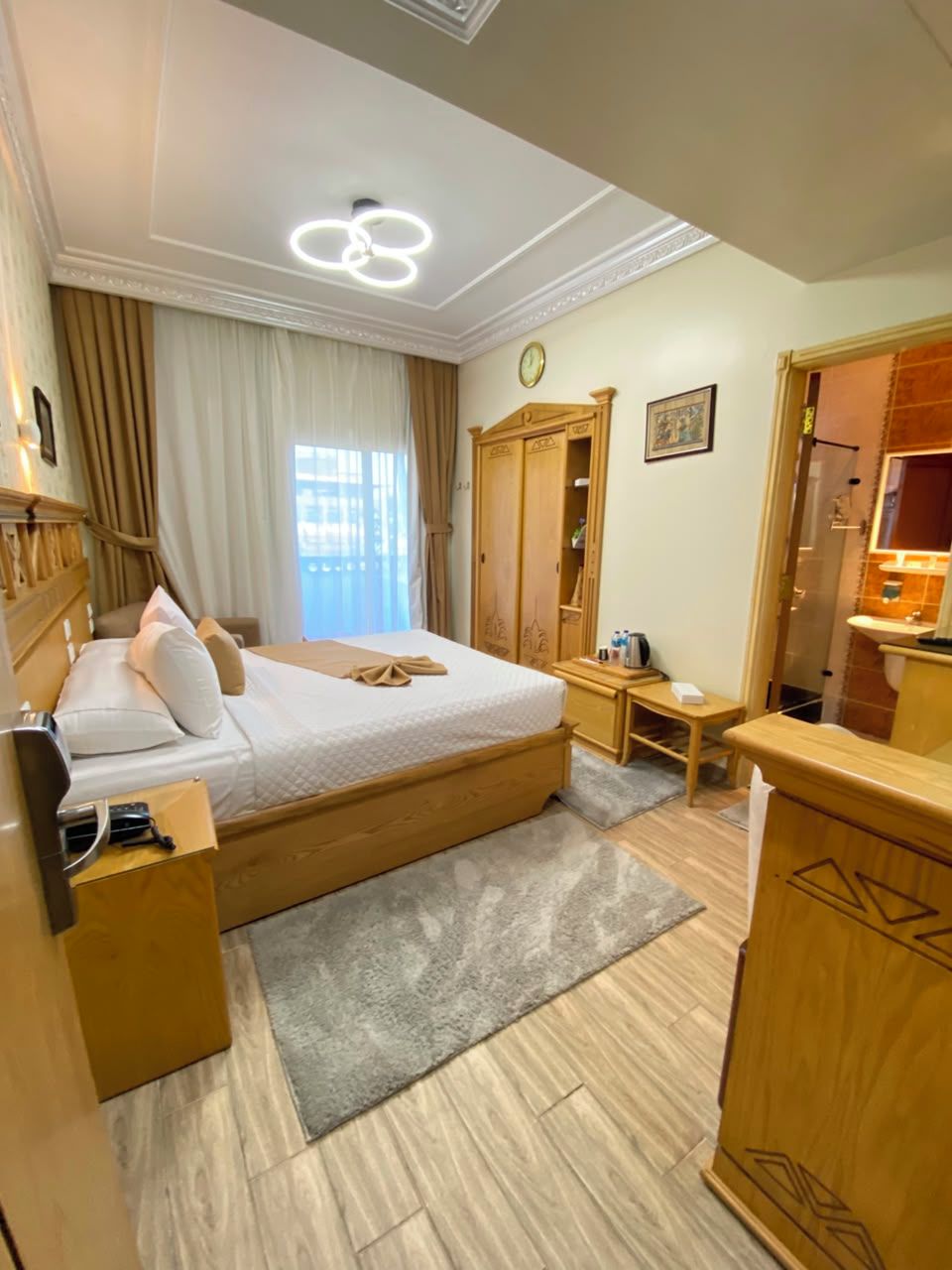 Una habitación de hotel con cama, mesita de noche, armario y baño con lavamanos y espejo.