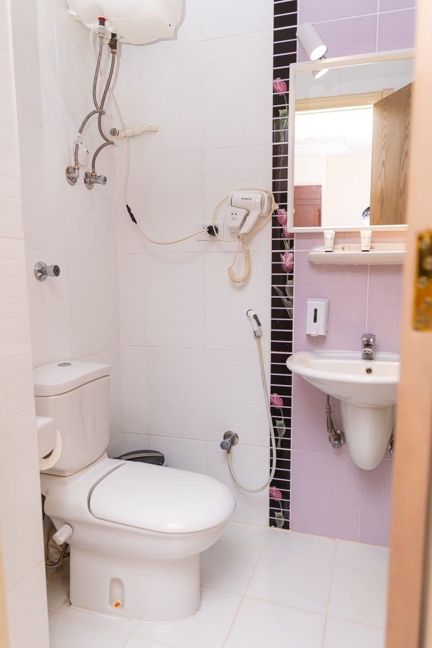 A bathroom with a toilet, a shower, and a sink.