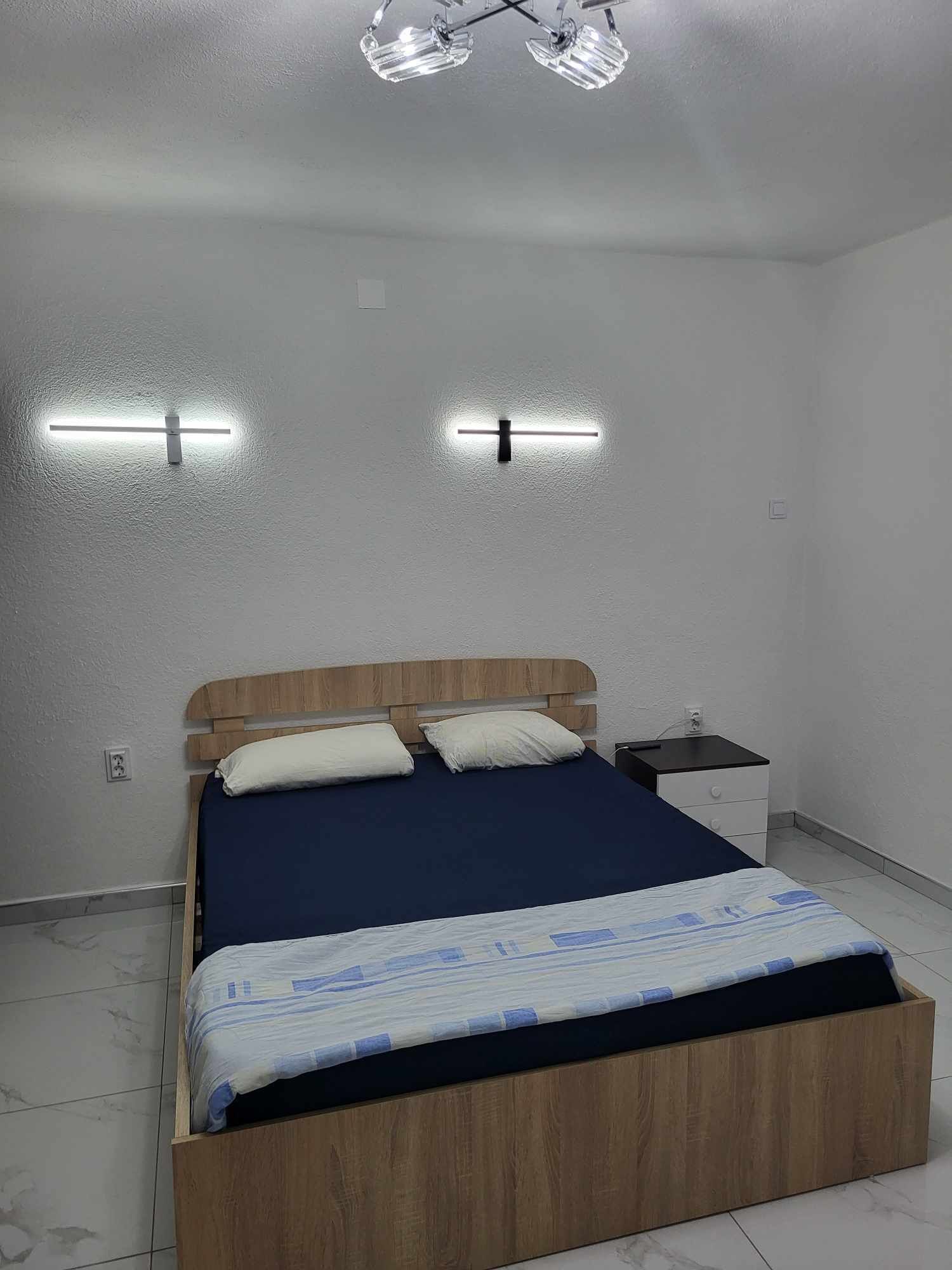 A bedroom with a wooden bed, two bedside tables, and a ceiling light fixture.