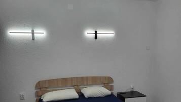 A bedroom with a wooden bed, two bedside tables, and a ceiling light fixture.