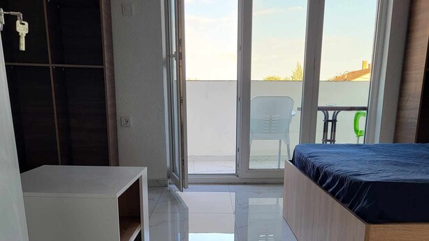 Un dormitorio moderno con cama, un rincón de descanso y un balcón con vistas.