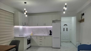 Cocina compacta con comedor, refrigerador y puerta con picaporte decorativo.
