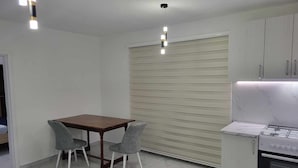 Una cocina con encimera de mármol, horno empotrado y comedor con mesa de madera y dos sillas.