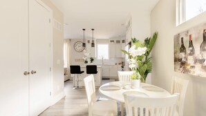 A bright, spacious kitchen with white cabinets, a dining area with a round table and chairs, and a large clock on the wall. - Luxurious Getaway Home with Rooftop Patio 10mins to downtown Durham and Duke (Durham)