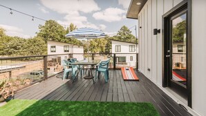 A deck with a table and chairs, a striped umbrella, and a view of neighboring houses. - Luxurious Getaway Home with Rooftop Patio 10mins to downtown Durham and Duke (Durham)
