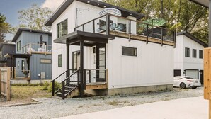 A modern two-story house with a balcony, a small outdoor seating area, and a car parked in the driveway. - Luxurious Getaway Home with Rooftop Patio 10mins to downtown Durham and Duke (Durham)
