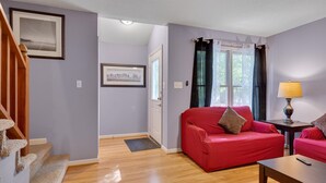 Ein Wohnzimmer mit einem roten Sofa, Holzboden, einer Lampe und einem gerahmten Bild an der Wand.