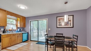 Eine moderne Küche mit Holzschränken, einem blauen Geschirrspüler und einem Essbereich mit Tisch und Stühlen.