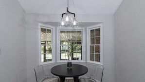 A dining area with a round table, clear chairs, and a pendant light. - 4 Bedroom Retreat — Close to Ft Benning: Modern, Cozy, and Mins to Everything! (Columbus)