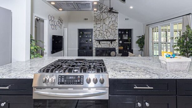 A modern kitchen with a gas stove, a built-in oven, and a stone backsplash. - 4 Bedroom Retreat — Close to Ft Benning: Modern, Cozy, and Mins to Everything! (Columbus)