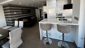 Une cuisine moderne dotée d’un îlot central, de tabourets de bar et d’un coin repas avec une table et des chaises.
