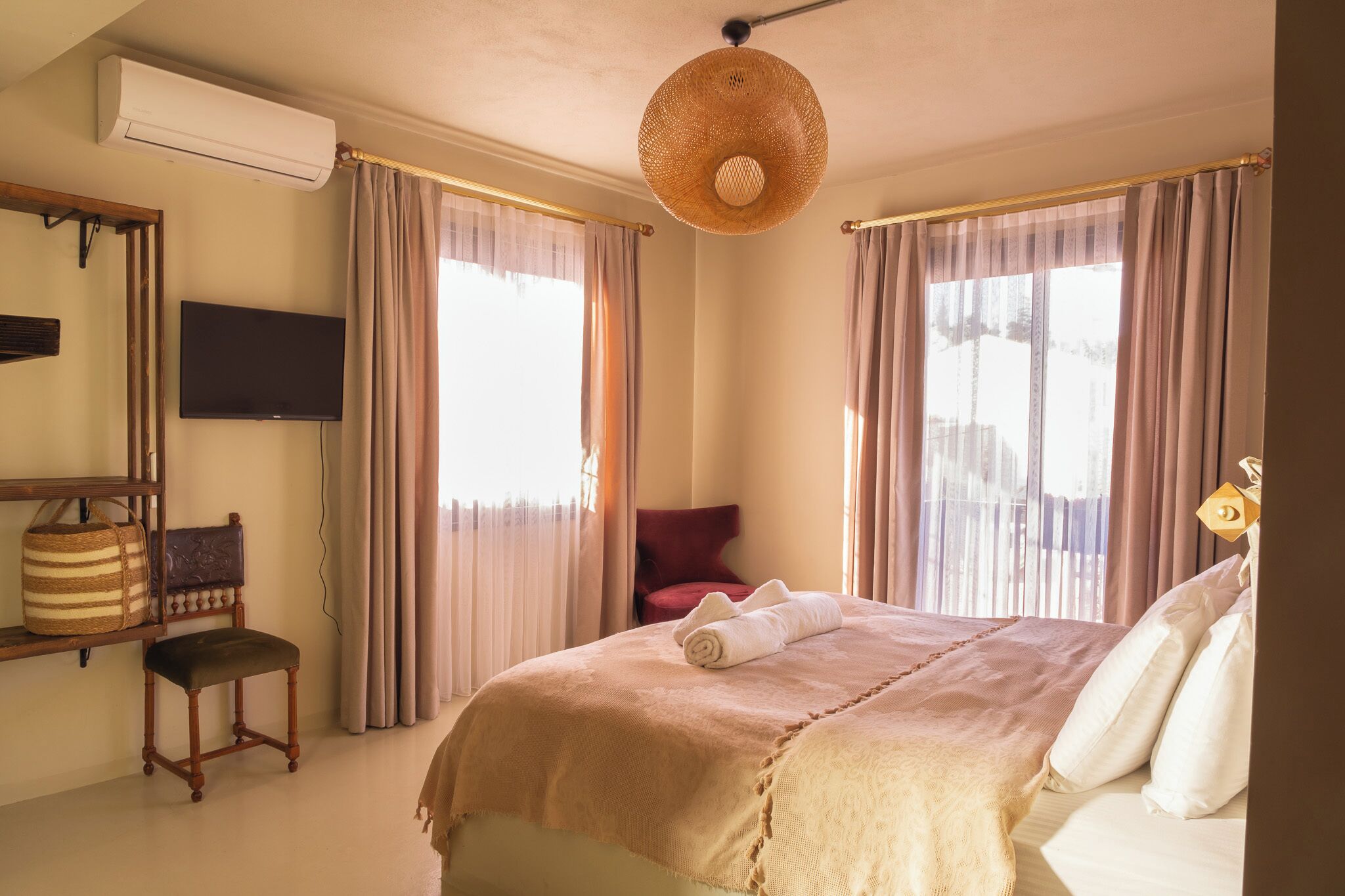 A bedroom with a bed, a chair, a television, and a large window with curtains.