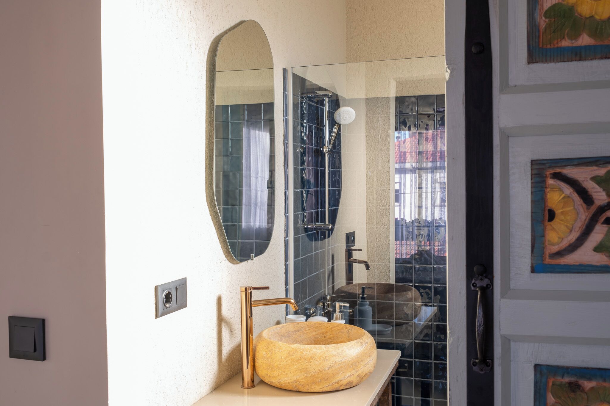 A bathroom with a round wooden sink, a mirror, and a shower.