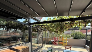 Eine Außenpatio mit einem Glastisch, Stühlen und einem Holzkasten.