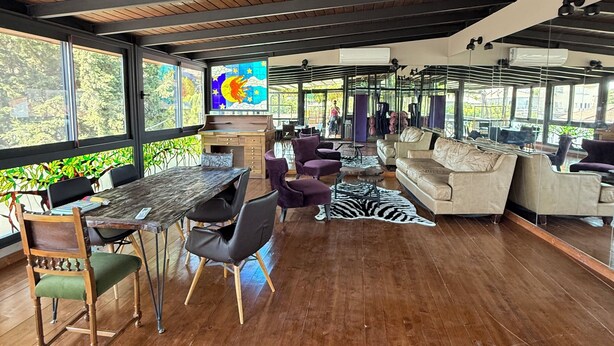 Ein geräumiger Wohnbereich mit Holzboden, einem Esstisch mit Stühlen, einer Couch und einem Fernseher.