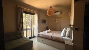 Ein Schlafzimmer mit Bett, einer Couch, einer Wand-Klimaanlage und Blick durch ein großes Fenster.