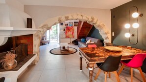 A modern kitchen with a stone archway leading to a dining area, a fireplace, and a staircase. - Belle Maison Charmante Typiquement Provençale (Meyrargues)