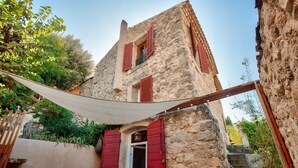 A stone building with red shutters, a wooden staircase, and a shaded outdoor area. - Belle Maison Charmante Typiquement Provençale (Meyrargues)