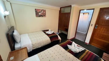 A hotel room with two beds, a wooden wardrobe, a mirror, and a painting on the wall.