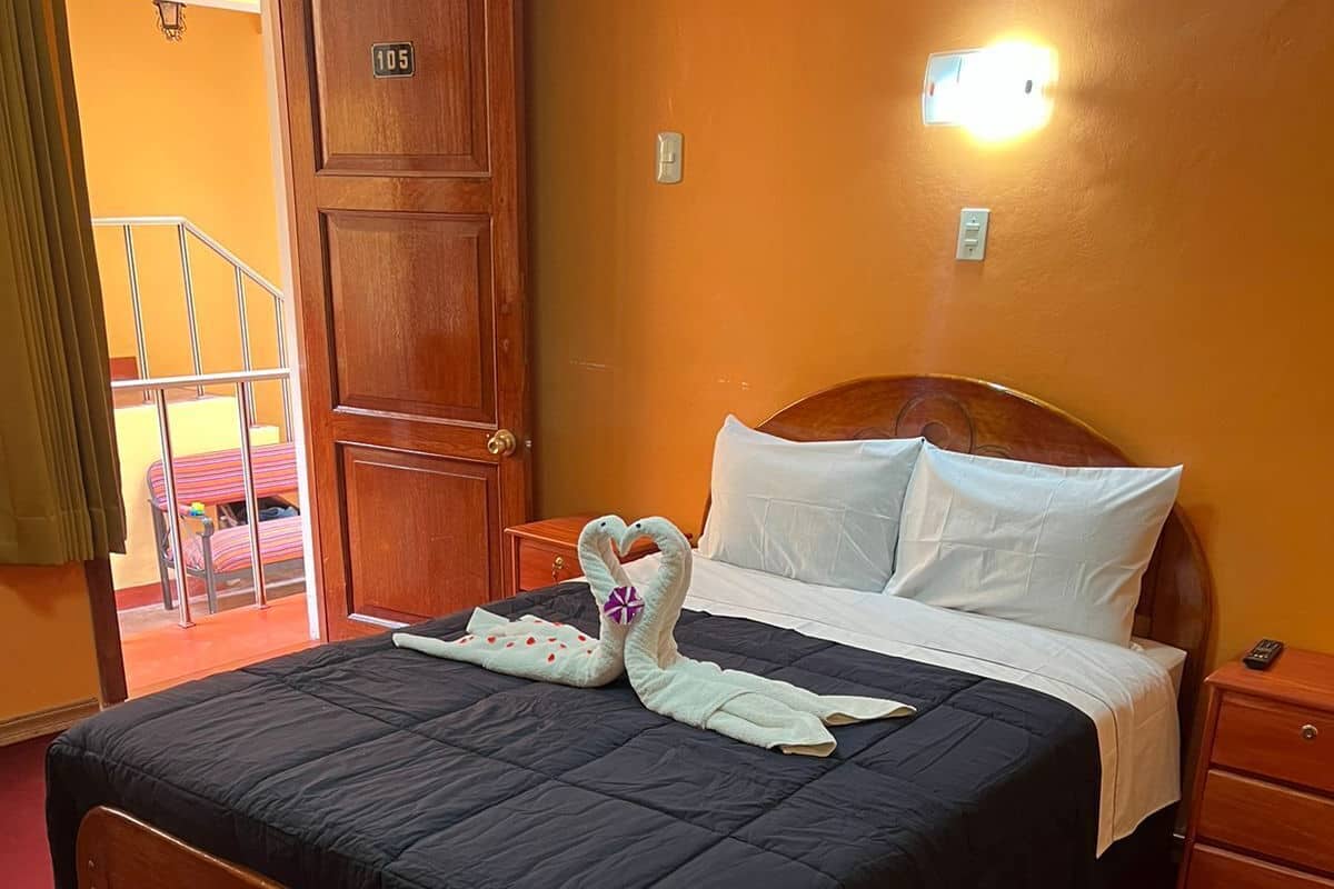 A hotel room with a wooden bed, a red carpet, a wooden wardrobe, and a balcony with a railing.
