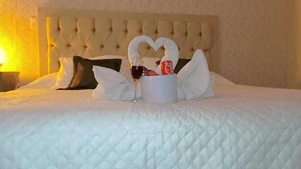 A bed with a heart-shaped arrangement of towels and a bottle of wine. - L ínea Divisoria (Zapotlan de Juarez)
