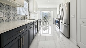 A modern kitchen with stainless steel appliances, a marble countertop, and a view to the dining area. - Spacious+cozy house, near the beach, heated pool. (Naples)