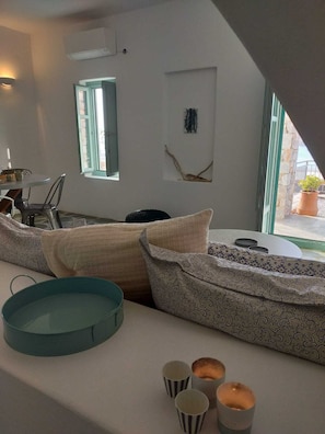 Un salon moderne avec un canapé, une table ronde et une fenêtre donnant sur la mer.