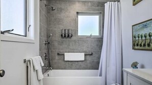 Un baño moderno con bañera, ducha y ventana.