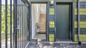 Una entrada protegida por un muro, con puerta y una escalera que conduce al interior.